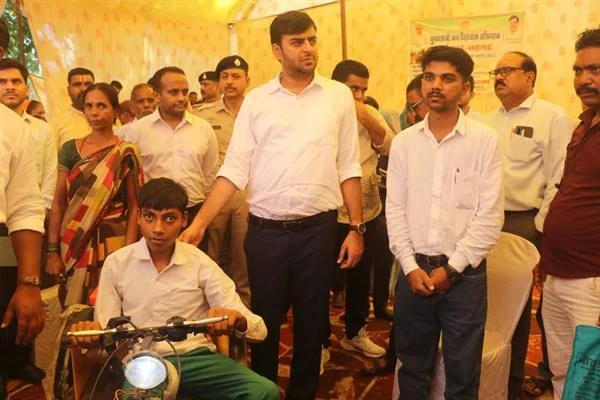 मोटराइज्ड तिपहिया साइकिल पर बैठे छात्र के साथ खड़े कलेक्टर और आसपास मौजूद लोग